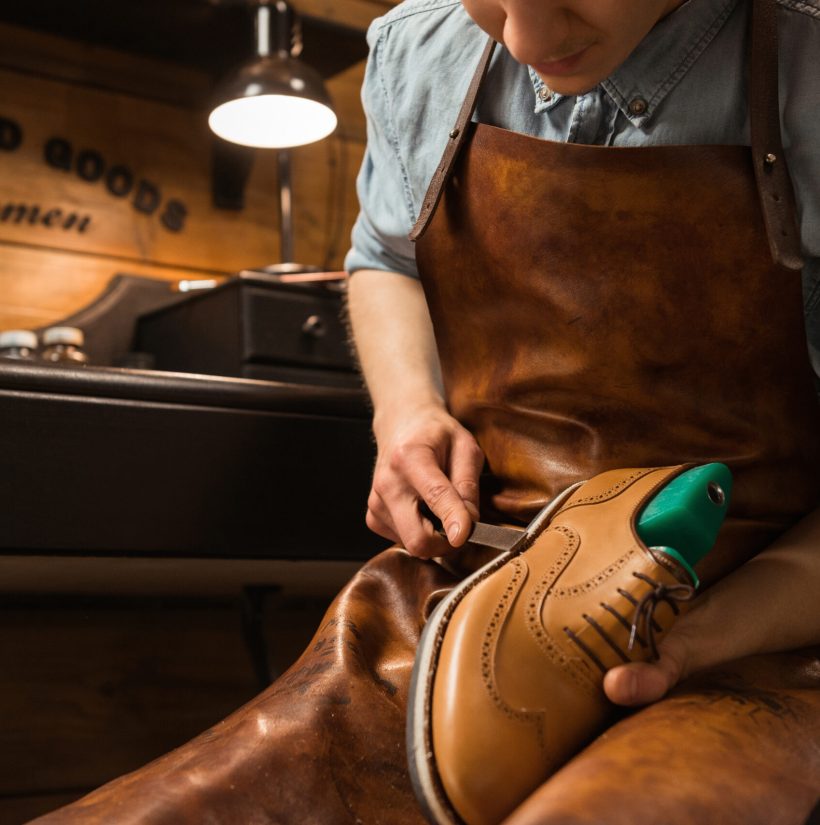 Cropped picture of young shoemaker in workshop making shoes.